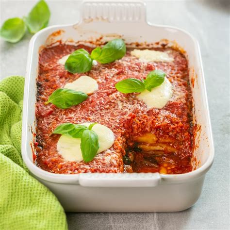 Una pirofila da forno con la parmigiana di melanzane pronta per essere infornata, con strati ben definiti.