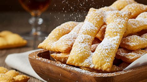 Una teglia di chiacchiere al forno dorate e spolverizzate di zucchero a velo.