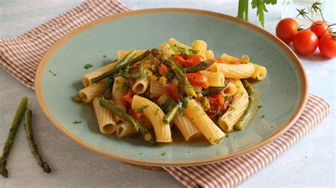 Primo piano di pasta fresca con asparagi, funghi e pomodorini fumante