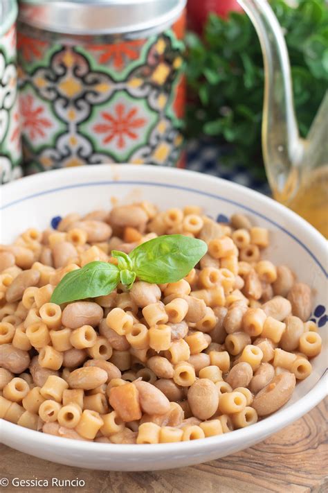 Immagine di un piatto fumante di pasta e fagioli, con ingredienti freschi disposti intorno