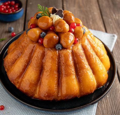Un babà napoletano classico, lucido e immerso nello sciroppo, con una decorazione di panna o frutta.