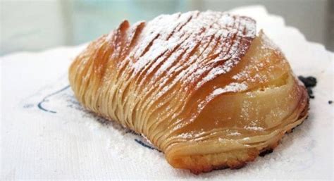 Primo piano di una sfogliatella riccia napoletana, mostrando la sfogliatura esterna e il ripieno cremoso.