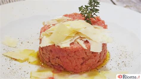 Piatto di carne cruda alla piemontese guarnito con scaglie di parmigiano e prezzemolo.