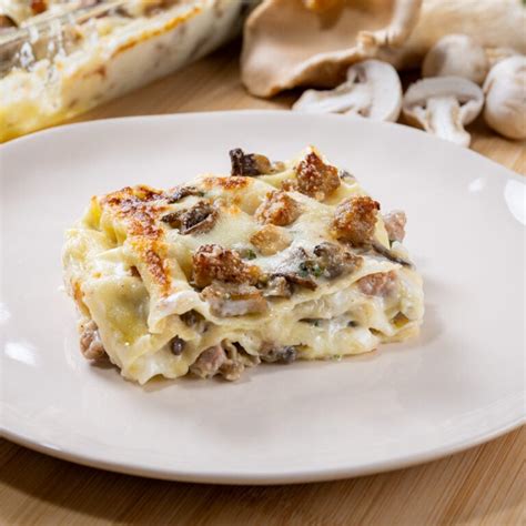 Strati di lasagne con funghi e salsiccia pronti per essere infornati.