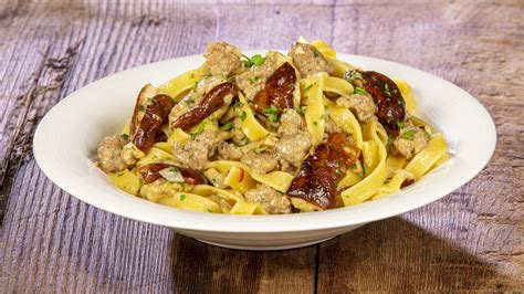 Un piatto fumante di tagliatelle con salsiccia e funghi.