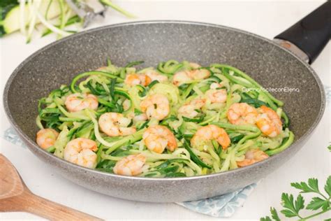 Primo piano di spaghetti di zucchine con gamberetti e pinoli tostati.
