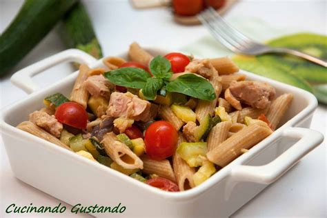 Una ciotola di pasta colorata con tonno, zucchine a cubetti, pomodorini ciliegino e olive nere