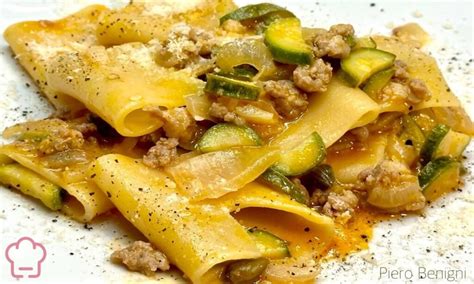 Immagine di paccheri con zucchine e stracciatella, guarniti con scorza di limone.
