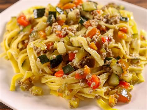 Immagine di tagliatelle integrali saltate con verdure colorate e stracciatella.