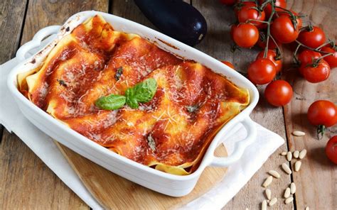 Una teglia fumante di lasagne al forno con melanzane fritte e polpettine, pronte per essere servite