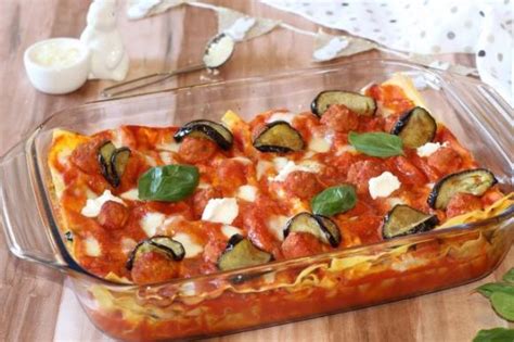 Vista dall'alto di una pirofila con strati di lasagna, sugo, melanzane e polpettine