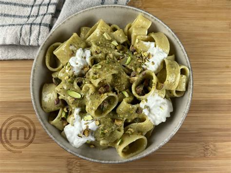 Illustrazione di un piatto di pasta al pesto di pistacchi fumante con guarnizione di pistacchi tritati e formaggio grattugiato.