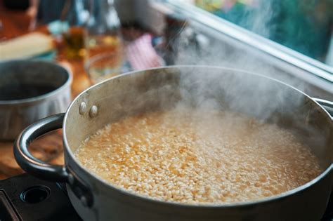 Immagine di un risotto in cottura in una casseruola, con il cuoco che aggiunge brodo caldo.