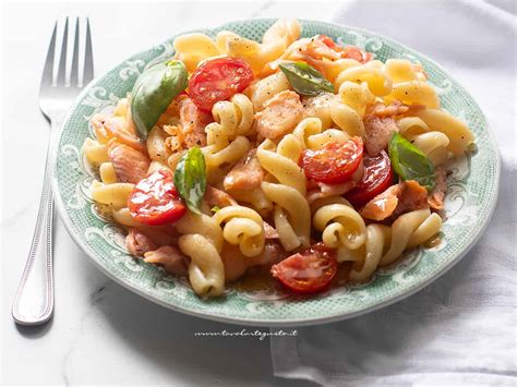 Immagine di un piatto di pasta fumante con salmone e gamberetti, guarnito con erba cipollina