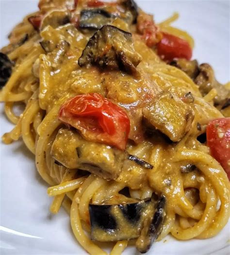 Piatto finito di spaghetti con fritti di capperi e melanzane su acqua di pomodoro