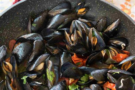 Padella con cozze che si aprono e pomodorini