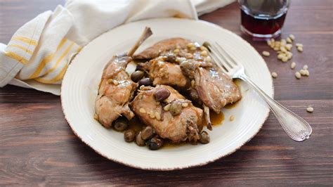 Ingredienti freschi per il coniglio alla ligure: olive taggiasche, pinoli, erbe aromatiche