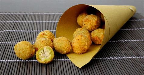 Una composizione di olive all'ascolana dorate e croccanti, pronte per essere servite in un cartoccio.
