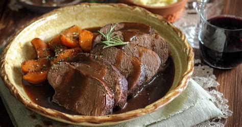 Immagine di un brasato che cuoce lentamente in una casseruola con vino rosso e verdure