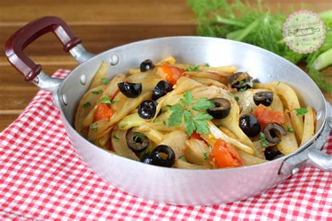 Immagine di finocchi affettati che cuociono in padella con pomodorini e olive.