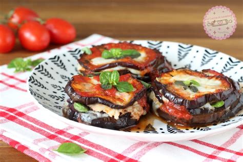 pirofila con involtini di melanzane ricoperti di salsa di pomodoro e formaggio grattugiato, pronti per essere infornati