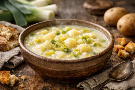 Immagine di una ciotola fumante di minestra di patate toscana con un filo d'olio e prezzemolo tritato