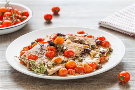 Ingredienti freschi per il pesce spada alla siciliana: pesce spada, pomodorini, capperi, olive, aglio, erbe aromatiche.