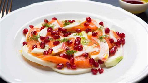 Carpaccio di salmone affumicato con finocchi e arancia, guarnito con melagrana e ciuffetti di finocchio