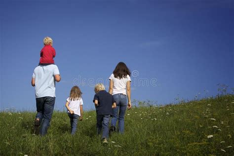 famiglia che cammina in un prato alpino con montagne sullo sfondo