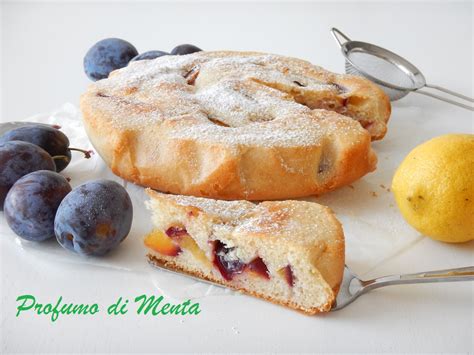 Una fetta di torta di prugne senza burro su un piatto, con prugne fresche nell'impasto e una spolverata di zucchero a velo.