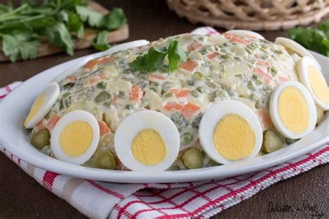 Ingredienti crudi per l'insalata russa disposti ordinatamente su un piano di lavoro