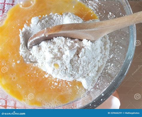 Immagine di una ciotola con farina setacciata e cocco, accanto a un'altra ciotola con uova sbattute e zucchero.