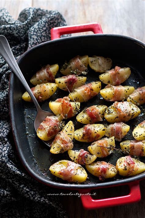 Diverse patate al forno con pancetta disposte su un piatto da portata, guarnite con rosmarino fresco.