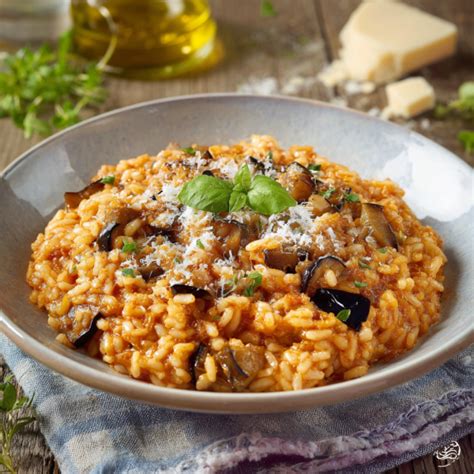 Un piatto di risotto cremoso con melanzane e pomodoro, guarnito con basilico