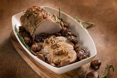 Immagine di un arrosto di maiale decorato con castagne e melagrana