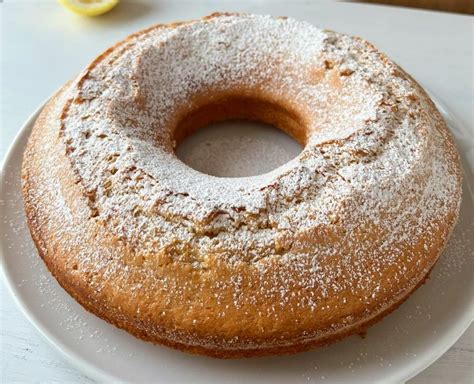 Foto di una ciambella al limone soffice e dorata, con un invitante centro marmorizzato di marmellata