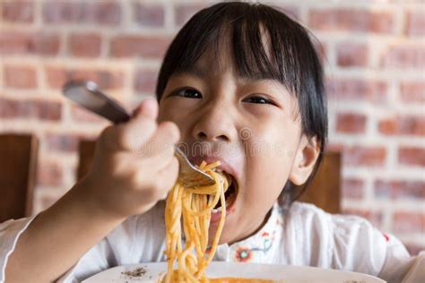 Bambini che mangiano pasta con espressioni felici, in un'ambientazione rustica
