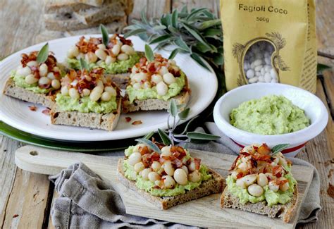 Immagine di crostini con fagioli, pesto di verza e speck croccante su un piatto da portata.