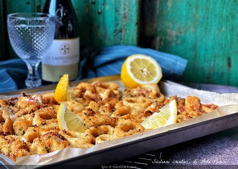 Un piatto di calamari impanati al forno serviti con spicchi di limone e una ciotolina di salsa.