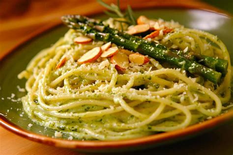 Un piatto di spaghetti conditi con una cremosa salsa di asparagi, guarnito con punte di asparagi freschi.