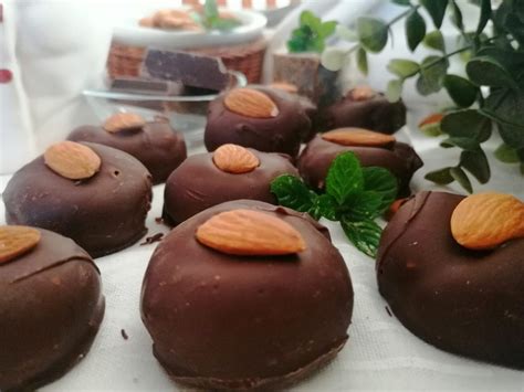 Primo piano di tartufini alle mandorle ricoperti di zucchero a velo, con alcuni spicchi di limone sullo sfondo.