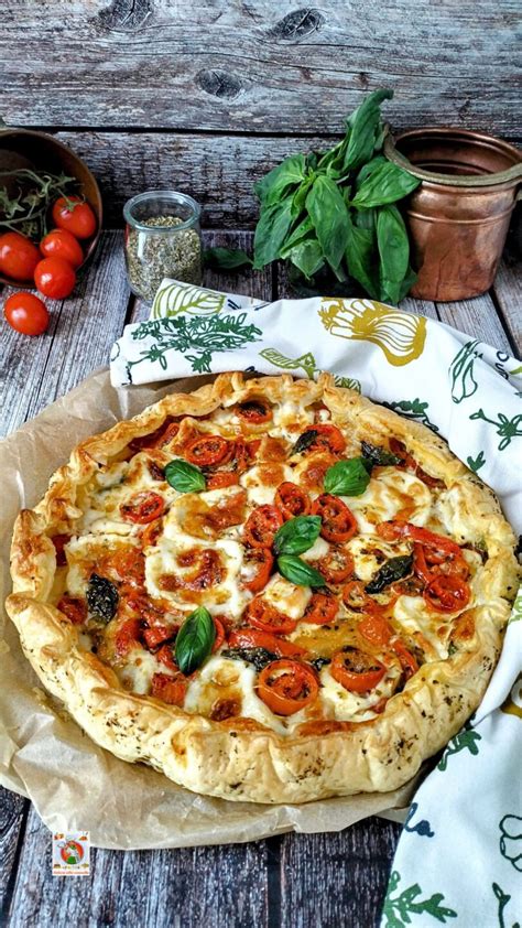 Immagine di una torta salata con pomodorini e mozzarella appena sfornata, con bordi dorati e ripieno filante