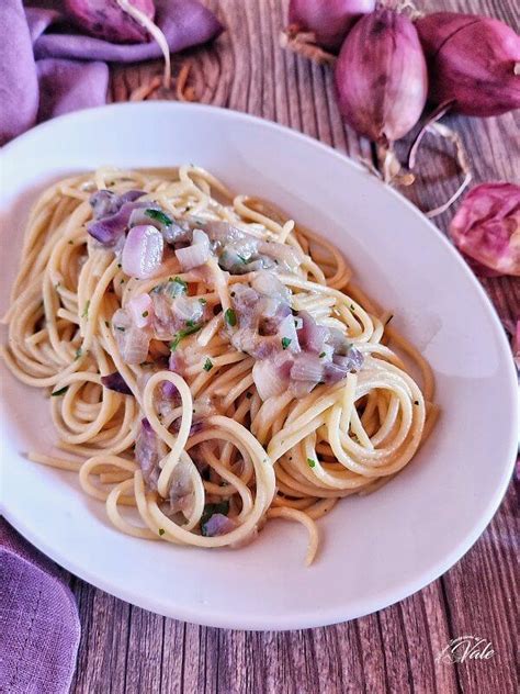 un primo piano di un piatto di pasta cremosa con cipolle e crostini di pane