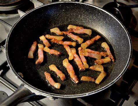 una padella con pancetta affumicata croccante che viene aggiunta alla crema di cipolle
