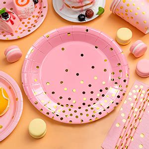 Tavolo da picnic allestito con stoviglie rosa pastello trasparenti e decorazioni a pois