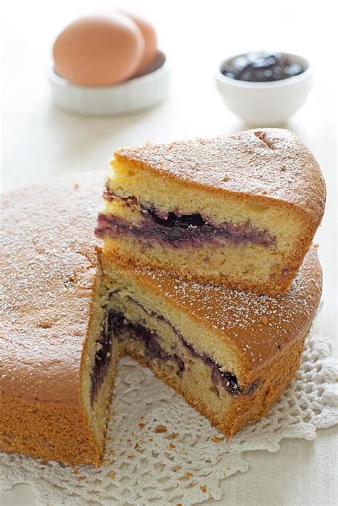 Primo piano di una fetta di torta versata con confettura e mirtilli, che evidenzia la consistenza del ripieno.