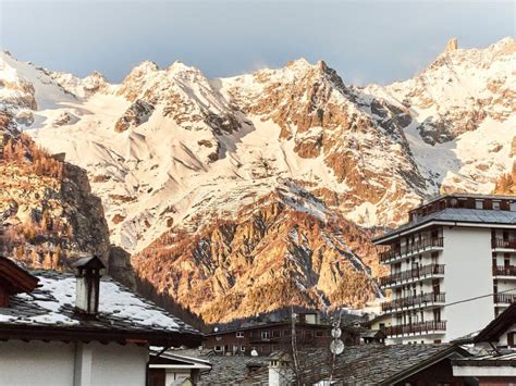 Panorama alpino della Valle d'Aosta con montagne innevate e un villaggio tradizionale