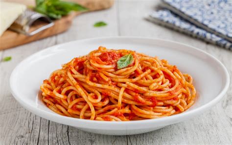 Un piatto di spaghetti al sugo di pesce fumante su un tavolo apparecchiato