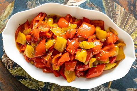 Una padella con peperoni che cuociono in agrodolce, con aglio, aceto e zucchero visibili.