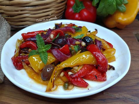 Un piatto di peperoni in agrodolce colorati, con strisce rosse e gialle, guarniti con prezzemolo.
